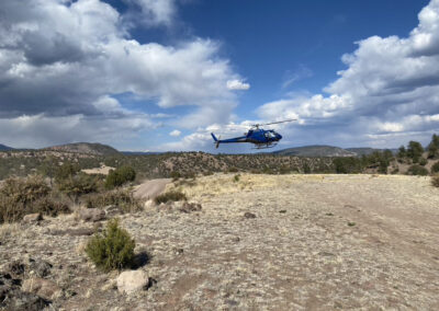 Blue helicopter flying over the mountains