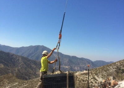 Man hooking up an item to be hauled by helicopter